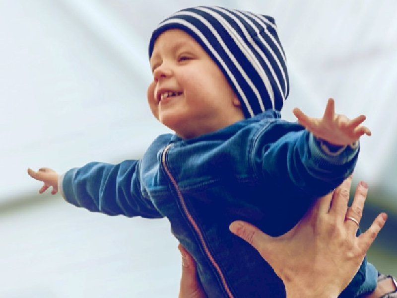 Vergnügtes Kind wird vor Haus in der Luft gehalten