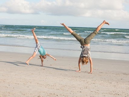 Zwei Personen, die am Strand Rad schlagen