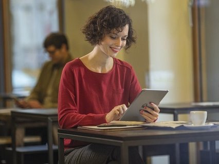 Beispielbild, junge Frau recherchiert am iPad im Kaffee
