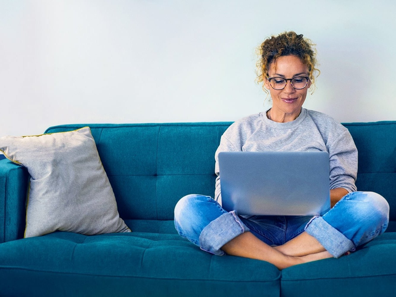 Beispielbild junge Frau recherchiert am Laptop auf einem Sofa