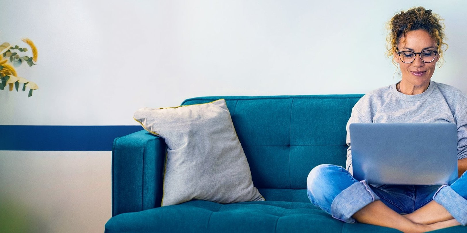 Beispielbild junge Frau recherchiert am Laptop auf einem Sofa