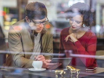 Beispielbild, junges Paar recherchiert am iPad, Blick durch Fenster